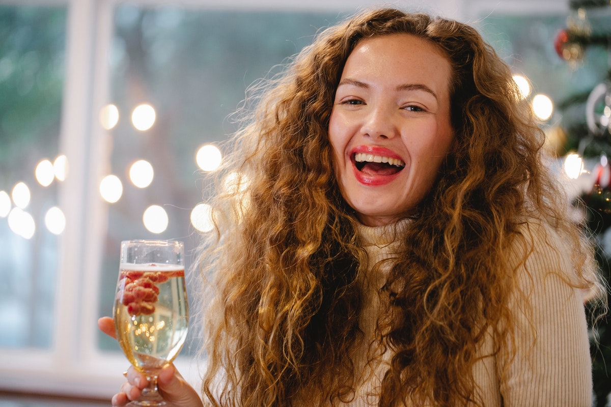 Mosolygó nő egy pohár itallal. Hogyan védjük májunk egészségét a karácsonyi ünnepek alatt?