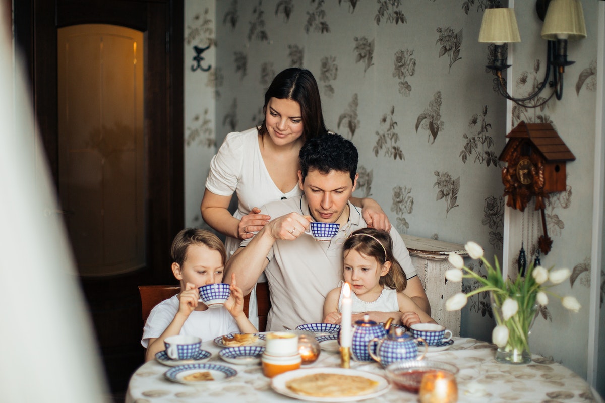Szülők Manuka mézes teát isznak gyermekeikkel a családi asztalnál. Természetes antibiotikumok - A Manuka méz lenyűgöző hatásai